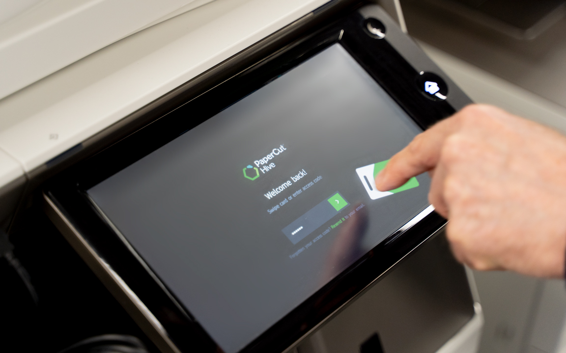  A photo of someone touching a Multi Functional Printer touchscreen that has PaperCut Hive software embedded 