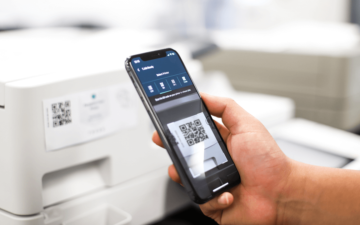  A photo of someone using PaperCut Hive mobile app to scan a QR code attached to a printer so they can release their print document 